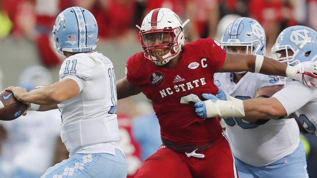 N.C. State defensive end Bradley Chubb (9) pressures North Carolina quarterback Nathan Elliott (11) as North Carolina’s Bentley Spain (75) tries to stop Chubb during in the Wolfpack’s game against the Tar Heels at Carter-Finley on Nov. 25, 2017.