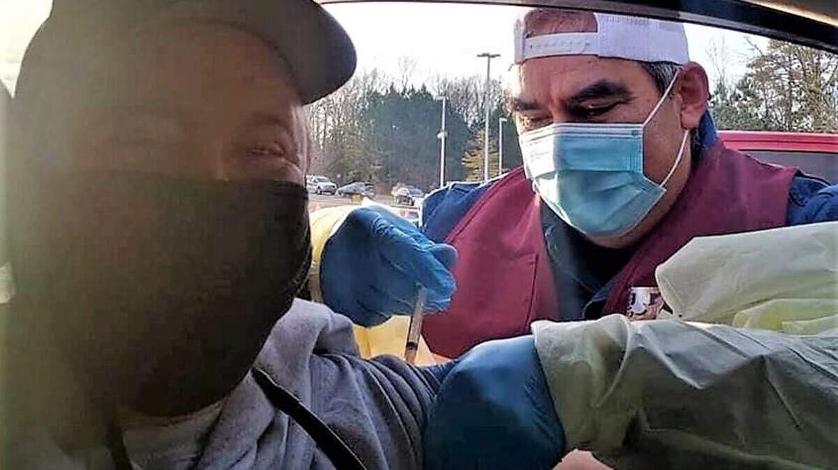 Eno Fire Department firefighter and emergency medical technician John Herrera administers the COVID-19 vaccine to a patient waiting in line at an Orange County Health Department drive-thru clinic in December at Cedar Ridge High School in Hillsborough.
