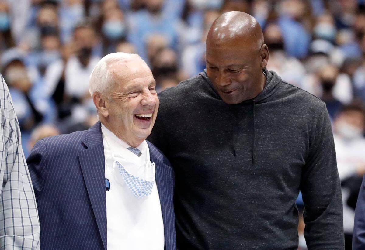 Roy Williams laughs with Michael Jordan as the 1981-82 national champion North Carolina basketball team is honored during UNC’s 100-80 victory over N.C. State at the Smith Center in Chapel Hill, N.C., Saturday, Jan. 29, 2022.