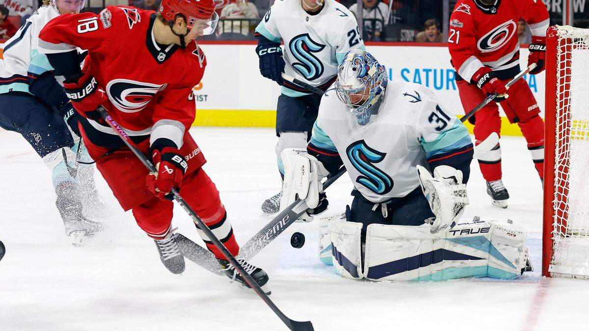 Carolina Hurricanes’ Jack Drury (18) looks back as the puck bounces off Seattle Kraken goaltender Philipp Grubauer (31) during the second period of an NHL hockey game in Raleigh, N.C., Thursday, Dec. 15, 2022. (AP Photo/Karl B DeBlaker)