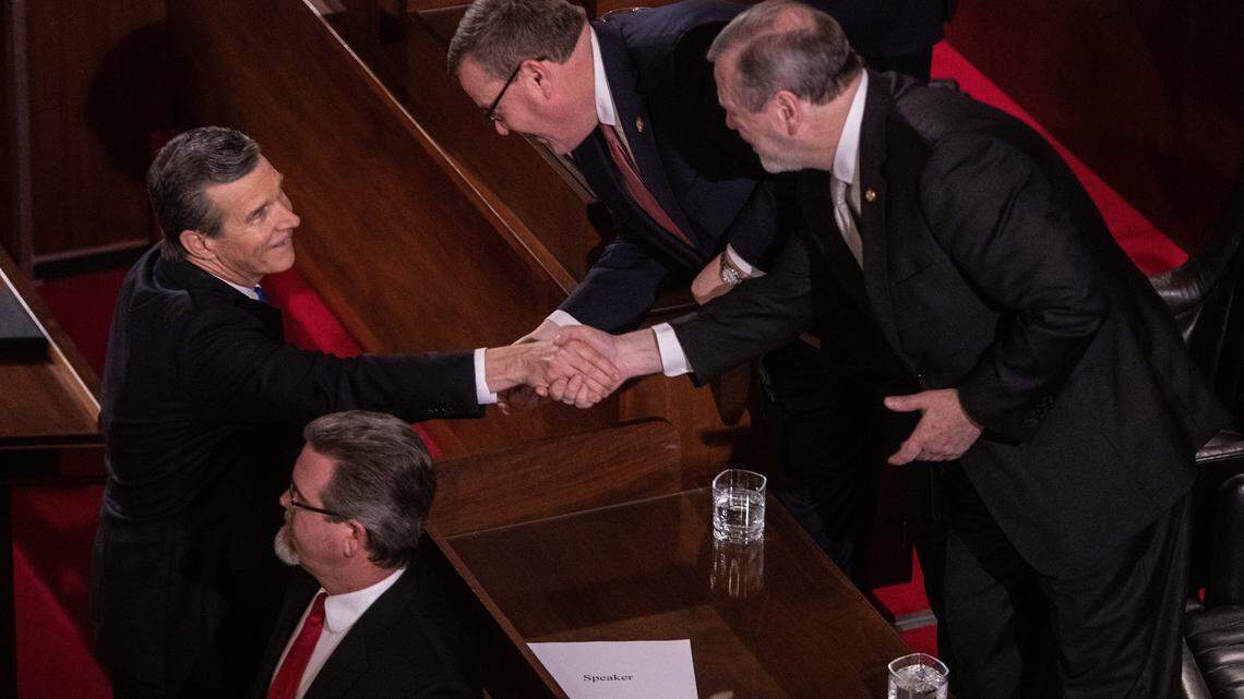 Gov. Roy Cooper, left, shakes hands with House Speaker Tim Moore, center and Senate Leader Phil Berger prior to Cooper’s biennial State of the State address to a joint session of the General Assembly at the Legislative Building Monday evening, Feb. 26, 2019.