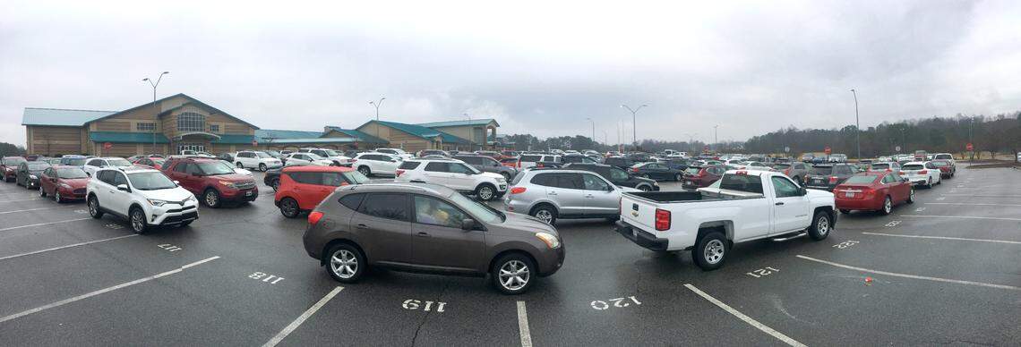 In this photo taken on an iPhone in panoramic mode, cars line up and wait during a drive-thru COVID vaccination clinic at West Johnston High School in Benson, N.C., Tuesday, January 12, 2021. The Johnston County Health Department clinic was for anyone 75 and older and was offered first come, first served for the first 500 who arrived.