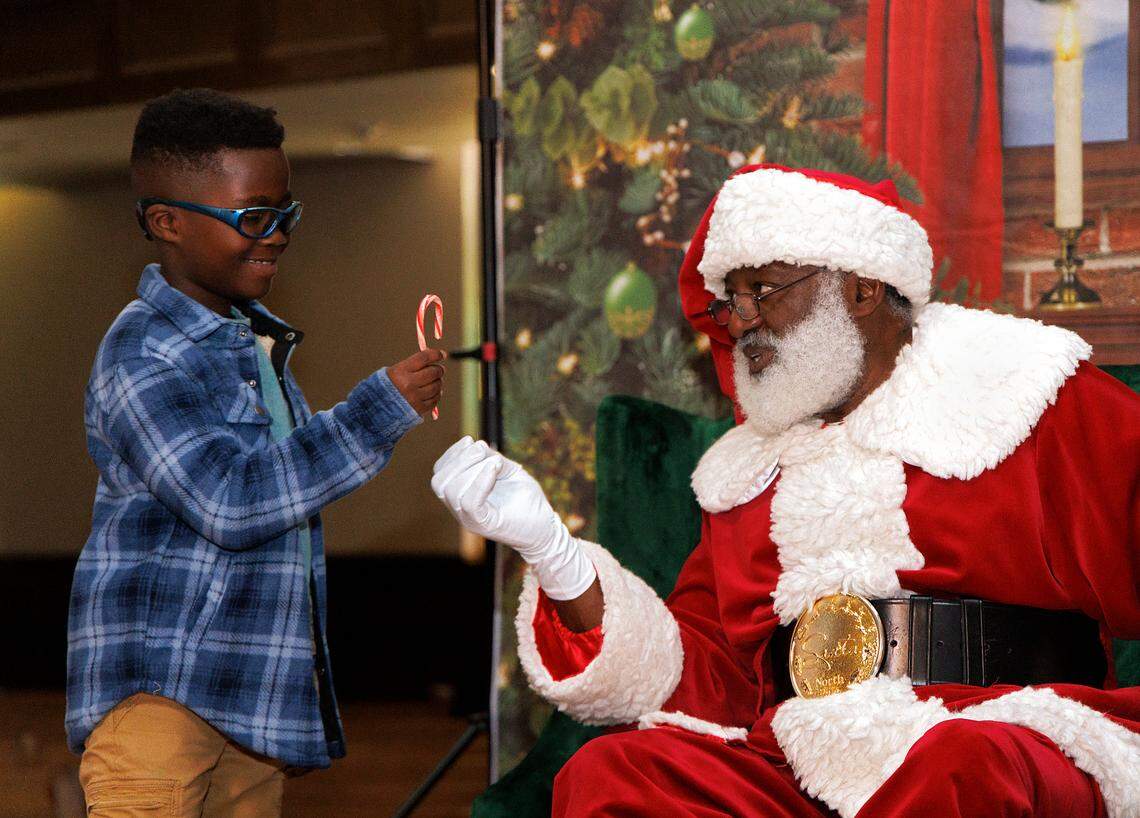 Allen Robinson, 7, smiles as he receives a candy cane from Santa during a Santas Just Like Me event at Hayti Heritage Center on Friday, Dec. 22, 2023, in Durham, N.C.