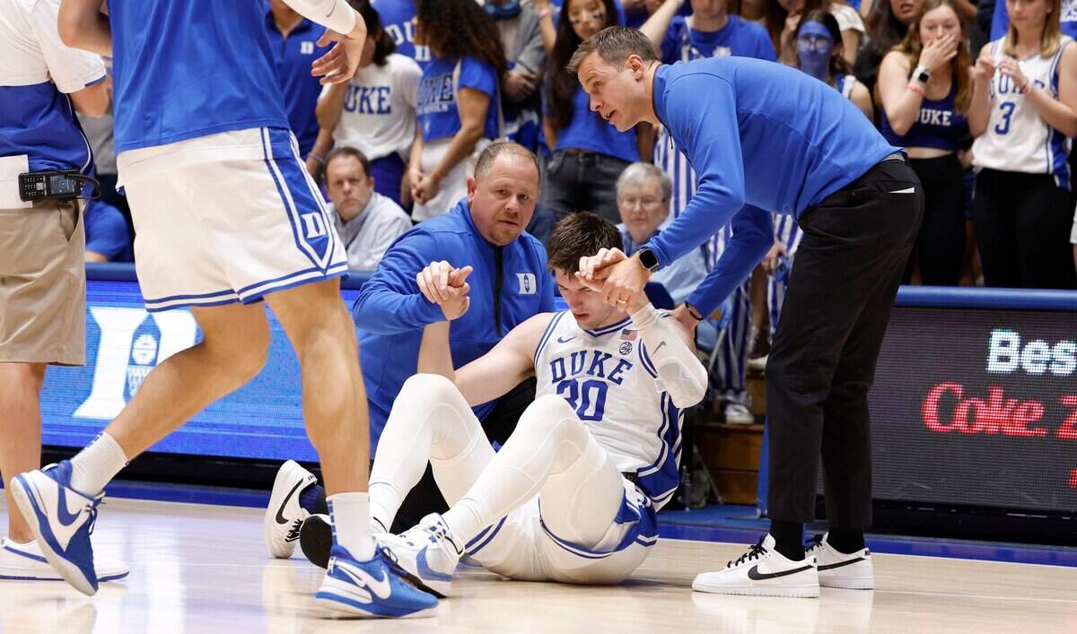 Duke trainer Jose Fonseca and head coach Jon Scheyer help Kyle Filipowski up after he was injured during the first half of Duke’s game against Bucknell at Cameron Indoor Stadium in Durham, N.C., Friday, Nov. 17, 2023.