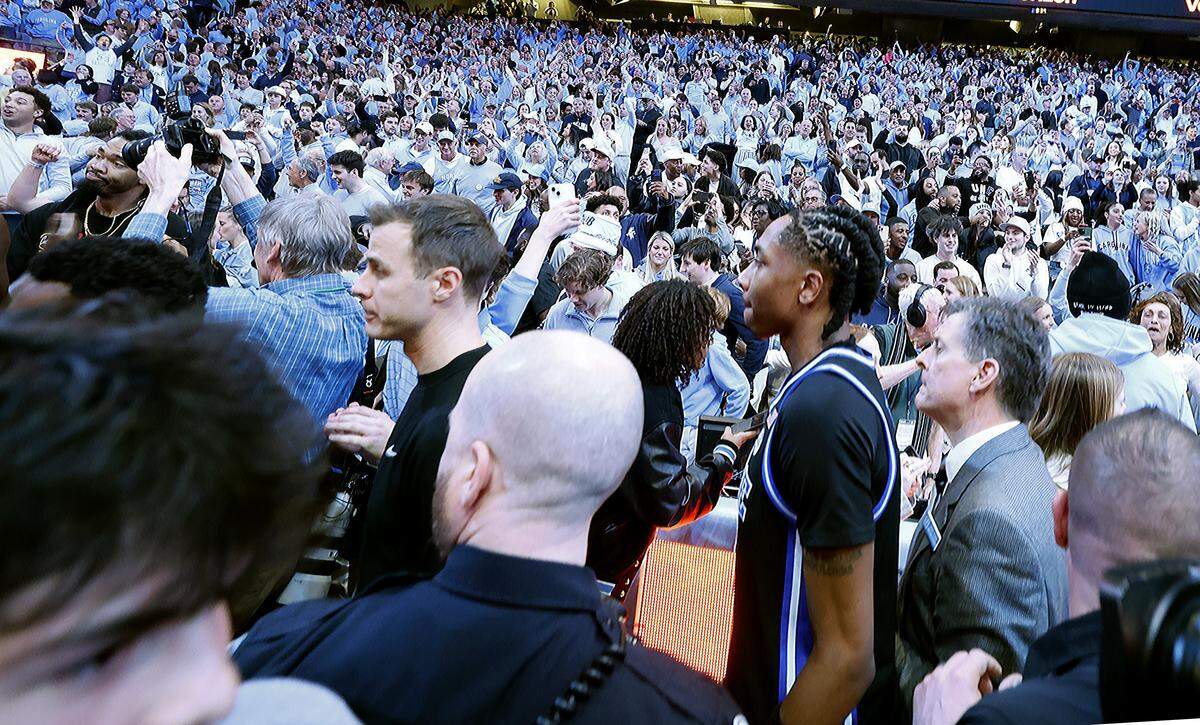 Duke head coach Jon Scheyer and Isaiah Evans (3) try to make their way off the court after UNC’s 71-68 victory over Duke at the Dean E. Smith Center in Chapel Hill, N.C., Saturday, Feb. 7, 2026.