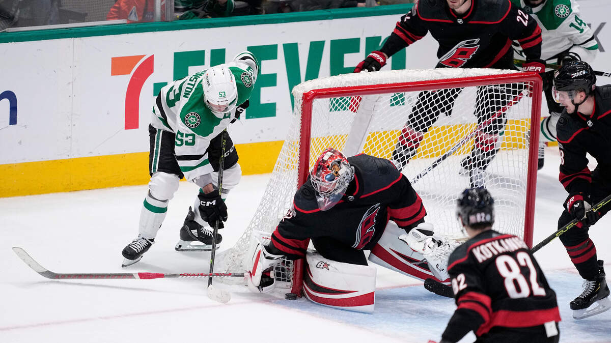 Dallas Stars center Wyatt Johnston (53) takes a shot that was stopped by Carolina Hurricanes goaltender Antti Raanta (32) as Jesperi Kotkaniemi (82), Brett Pesce (22) and Martin Necas (88) help defend during the third period of an NHL hockey game Wednesday, Jan. 25, 2023, in Dallas. (AP Photo/Tony Gutierrez)