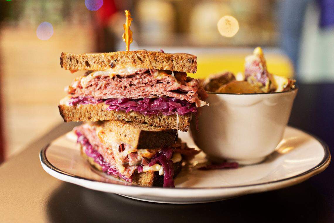 Raleighs (ish) delicatessen makes a housemade pastrami or corned beef sandwich with Swiss, Super Russian, braised purple cabbage, on Boulted Bread rye. It is served here with a side of potato salad made with charred onions and dressed in olive oil and mustard.