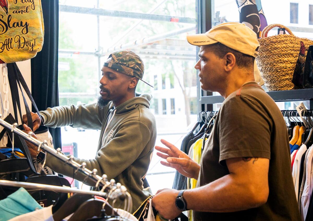 Johnny Hackett, left, helps a customer, Richard Saxton, pick a tote bag in the Black Friday Market, which opened the storefront downtown in December 2019 to sell products and art from small, mostly Black-owned businesses, on Wednesday, Aug 4, 2021, in Raleigh, N.C.