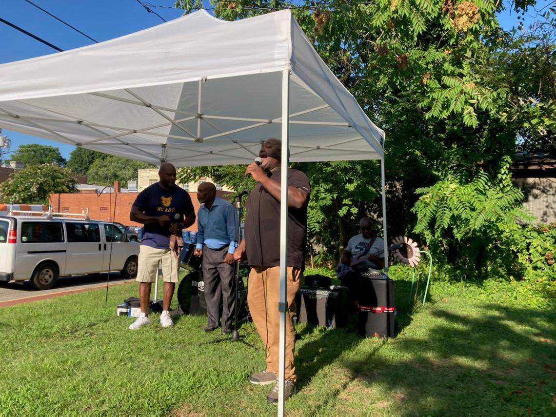 Charles Collins, Karl Wade and Demorris Tucker sing, accompanied by guitarists and a drummer, under a tent in front of the Margaret Lane Gallery in Hillsborough. 