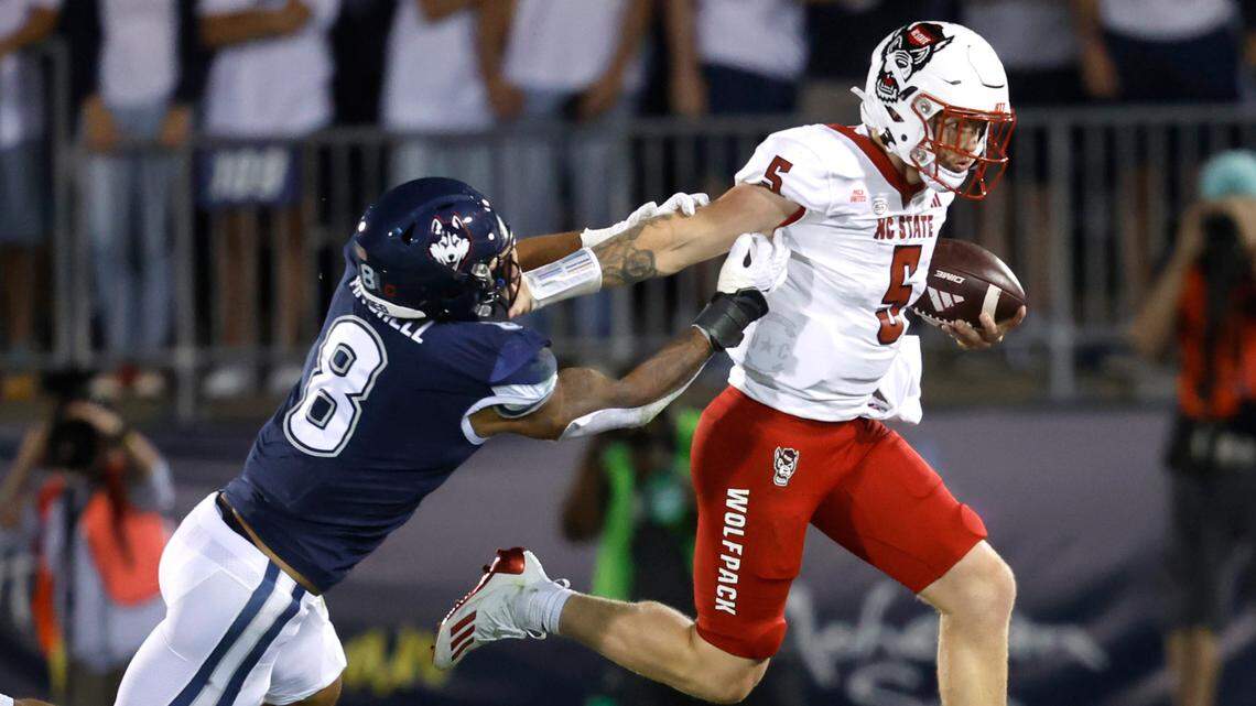 N.C. State quarterback Brennan Armstrong (5) stiff-arms Connecticut linebacker Jackson Mitchell (8) as he runs for yards during the first half of N.C. State’s game against UConn at Rentschler Field in East Hartford, Conn. Thursday, August 31, 2023.