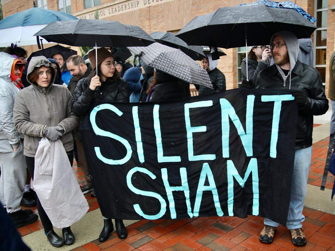 Protesters huddle under umbrellas while holding a large sign reading ÒSilent ShamÓ during protests over the recent Silent Sam deal made by the UNC Board of Governors.