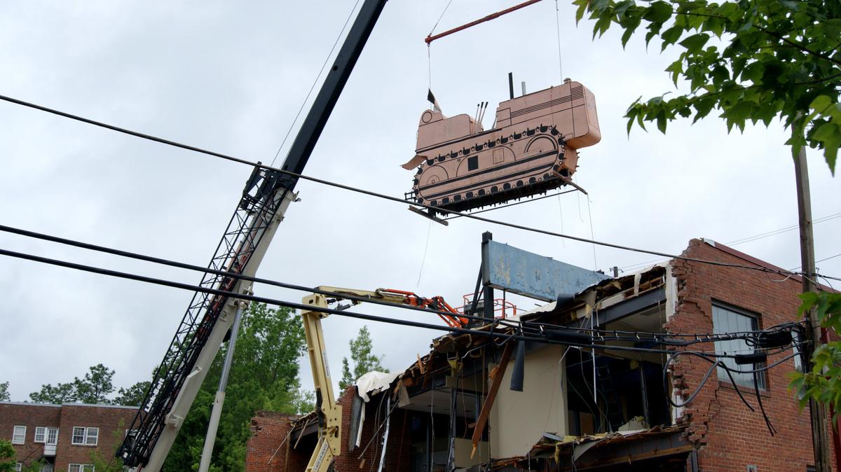 The iconic bulldozer sign on Hillsborough Street came down Thursday, making way for student apartments as the old N.C. Equipment  Co. building is demolished.