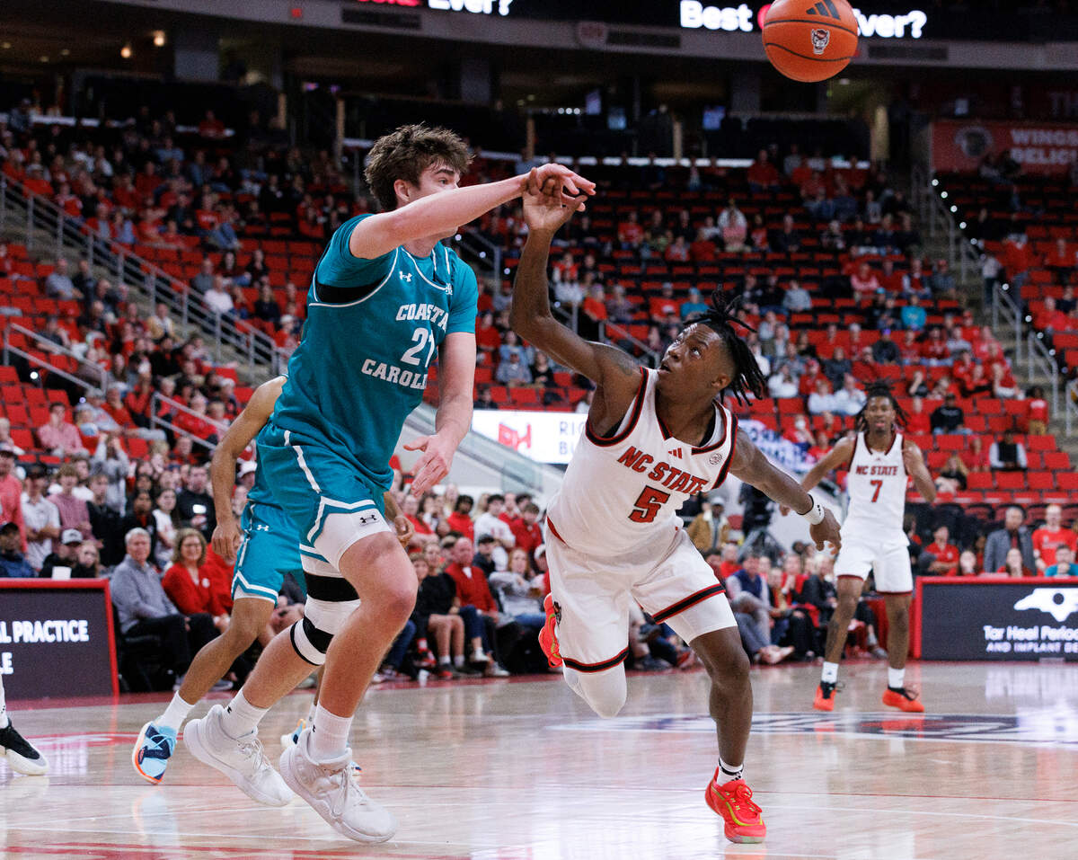 N.C. State’s Trey Parker and Coastal Carolina’s Noah Amenhauser lunge for a loose ball during the second half of the Wolfpack’s 82-70 win on Wednesday, Nov. 13, 2024, at Lenovo Center in Raleigh, N.C.