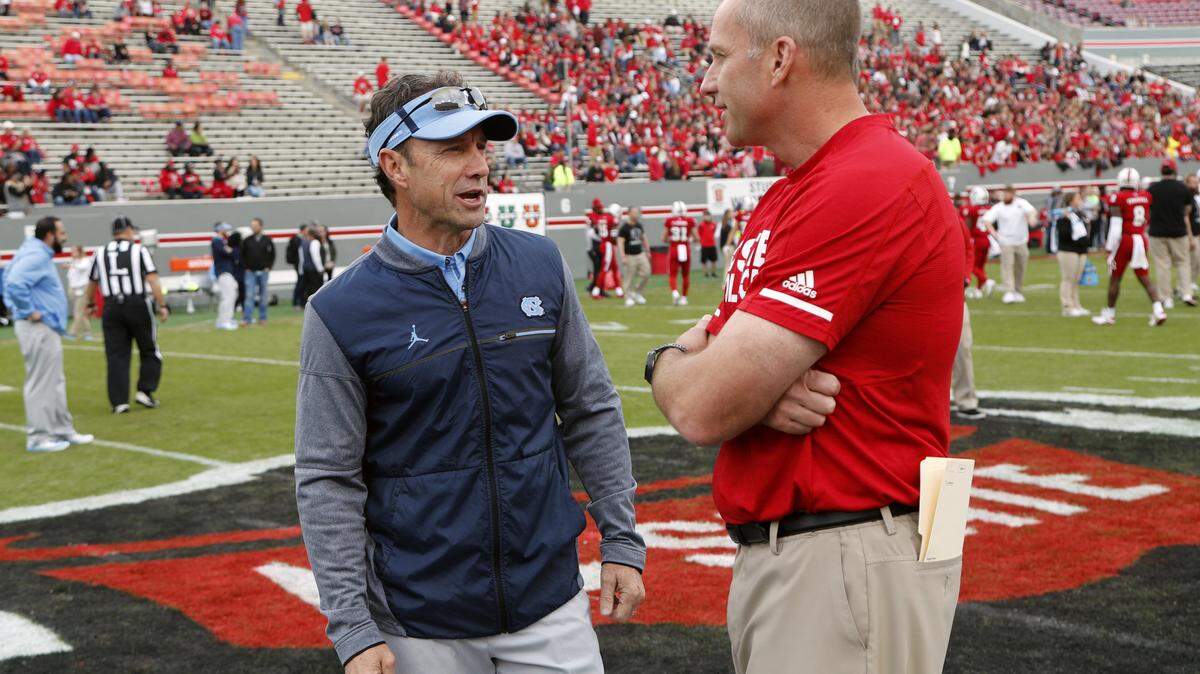 UNC head coach Larry Fedora, left, and NC State head coach Dave Doeren meet at the center of the field before their game at Carter-Finley Stadium on Nov. 25, 2017.