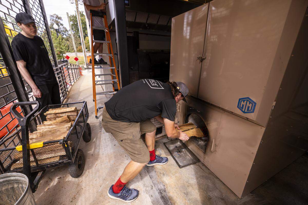 Smoke captain Jordan Reading loads wood into a M&M BBQ smoker at Lawrence Barbecue in Cary. The restaurant uses oak and hickory.