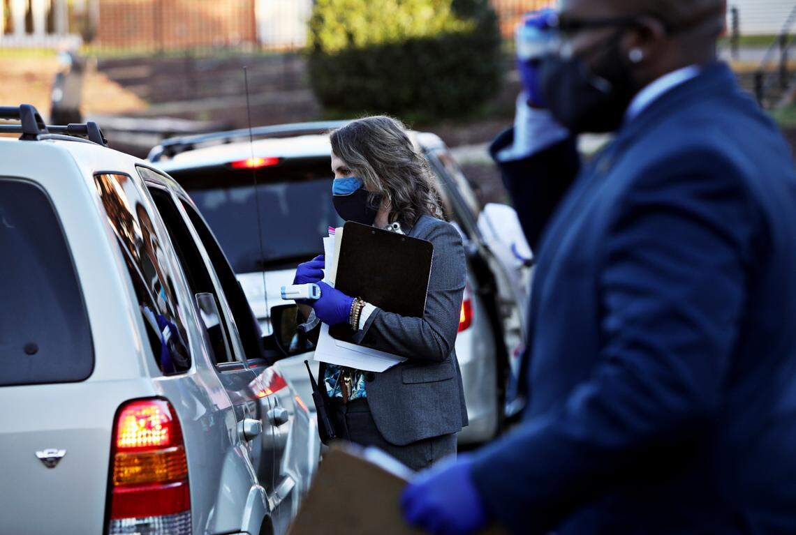 Carroll Middle School principal Elizabeth MacWilliams, center, screens a student in carpool before the first day of in-person school for some students on Monday, Nov. 9, 2020.