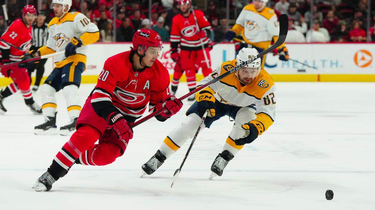 Dec 15, 2023; Raleigh, North Carolina, USA; Carolina Hurricanes center Sebastian Aho (20) cuts with the puck past Nashville Predators center Tommy Novak (82) during the first period at PNC Arena. Mandatory Credit: James Guillory-USA TODAY Sports