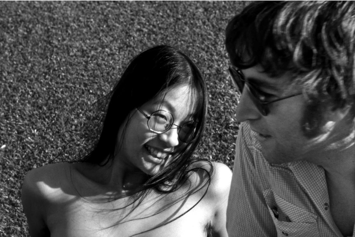 May Pang and John Lennon enjoy a relaxed moment in this candid shot from the exhibit, “The Lost Weekend: The Photography of May Pang,” coming to Chapel Hill and Charlotte in November 2024.