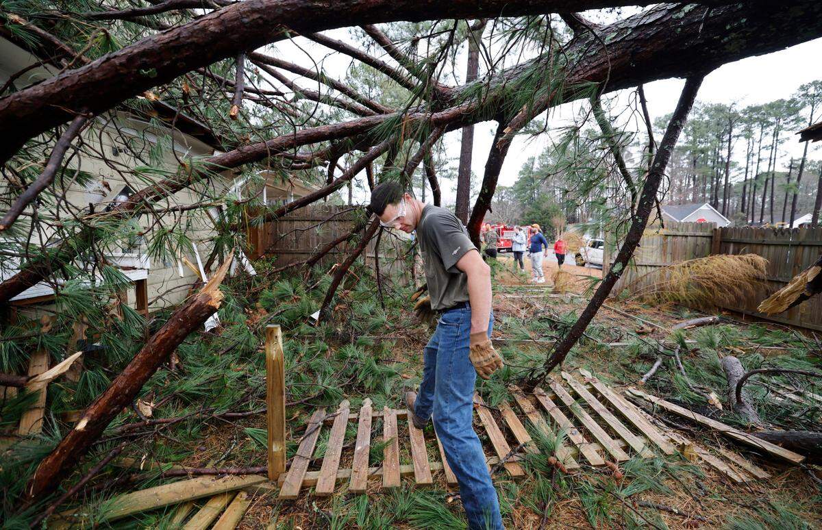 William Woodall, an off duty Garner firefighter, helps clean up knocked down trees that hit a home on Buckhorn Road in Garner, N.C., Sunday, Dec. 10, 2023.