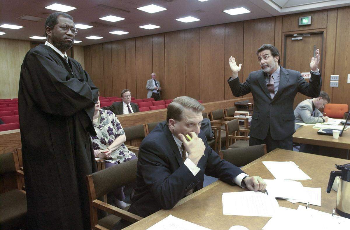 Judge Orlando Hudson(left, listens as Michael Peterson’s defense attorney David Rudolf argues a point in a May 29, 2003 hearing about media access to Peterson’s murder trial. Durham District Attorney Jim Hardin is seated in the foreground and Peterson is seated in the background at right.