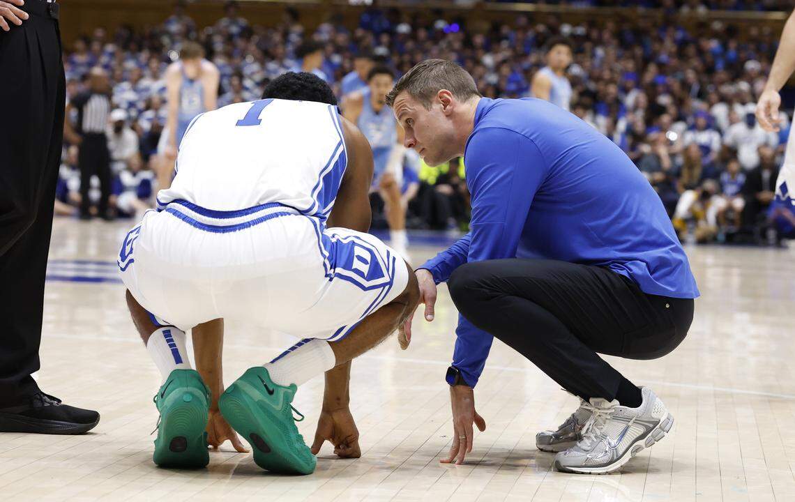 Duke head coach Jon Scheyer checks on Caleb Foster (1) after he was injured during the first half of Duke’s game against UNC at Cameron Indoor Stadium in Durham, N.C., Saturday, March 7, 2026.