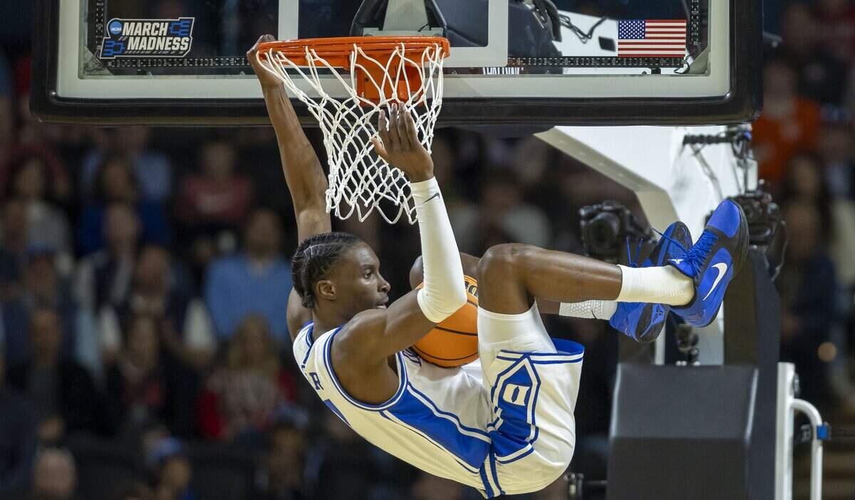 Duke guard Dame Sarr (7) hangs on the rim after a dunk over Siena guard Brendan Coyle (21) to pull the Blue Devils to within two points in the second half on Thursday, March 18, 2026, during the first round of the NCAA Tournament at Bon Secours Arena in Greenville, S.C.