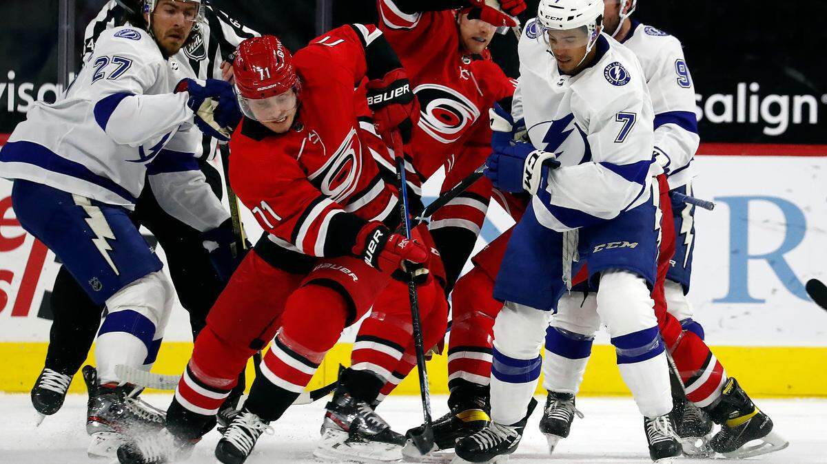 Carolina Hurricanes’ Jesper Fast (71) retrieves the puck following a face-off with Tampa Bay Lightning’s Mathieu Joseph (7) and Ryan McDonagh (27) looking on during the first period of an NHL hockey game in Raleigh, N.C., Saturday, Feb. 20, 2021. (AP Photo/Karl B DeBlaker)