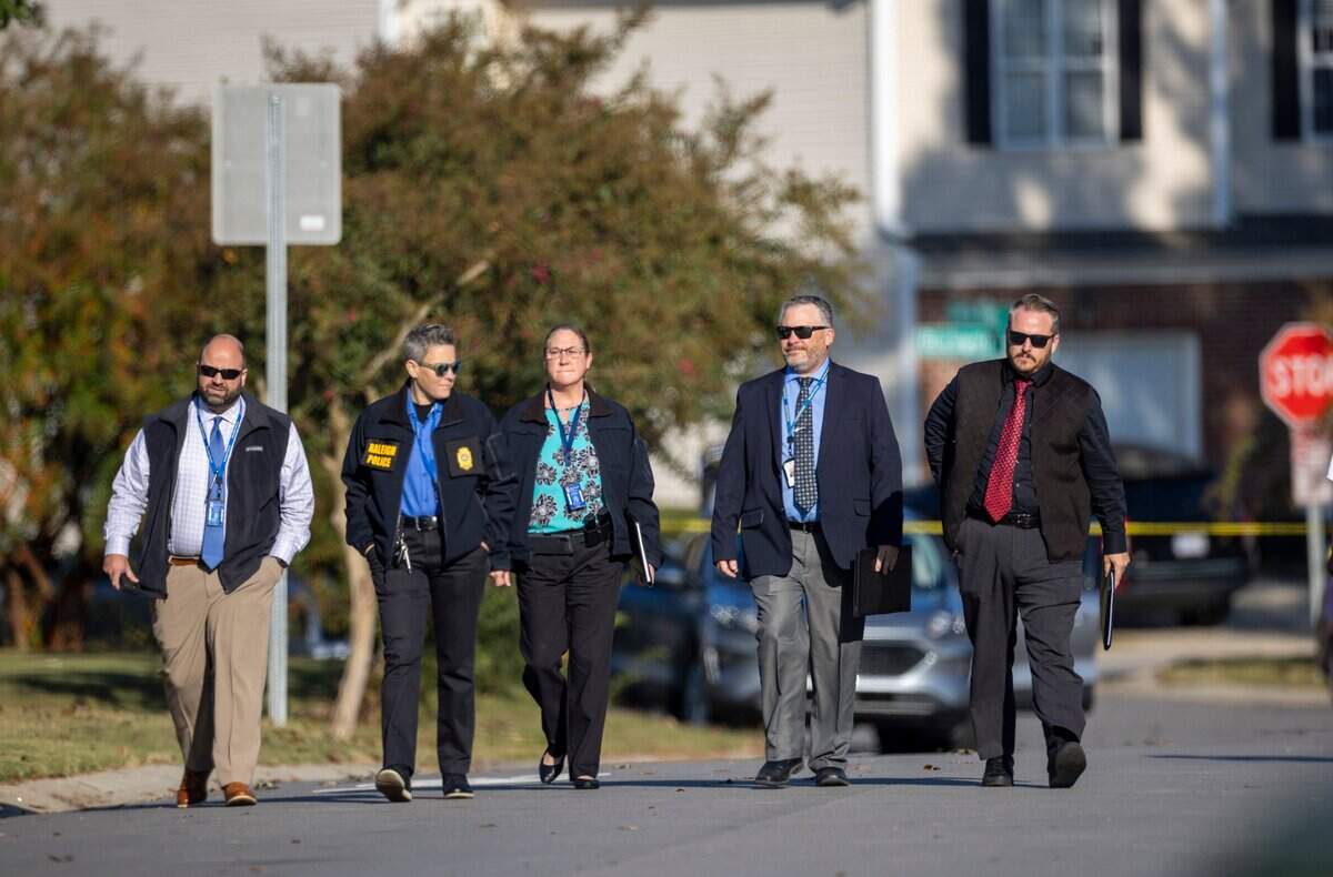 Law enforcement walk down Castle Pines Drive in the Hedingham neighborhood on Friday morning, October 14, 2022 in Raleigh, N.C. as they continue to investigate the shooting that killed 5 people including an off-duty police officer on Thursday.