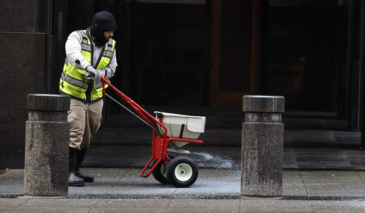 Steven Lesane, a specialist with the Wake County General Services Administration, applies ice melt outside the Wake County Justice Center in Raleigh on Monday, Dec. 8. Surfaces that received precipitation on Monday and did not dry out could freeze overnight. 