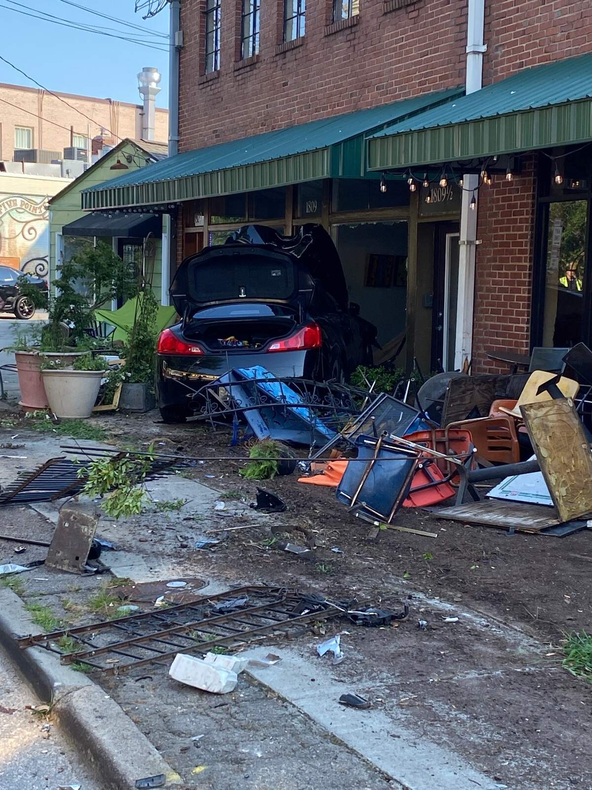 A car whose driver lost control while speeding on Glenwood Avenue into the Five Points neighborhood in Raleigh, N.C. demolished the patios outside of businesses and landed in Leslie Jandrain’s art gallery on Sunday, July 4, 2021.