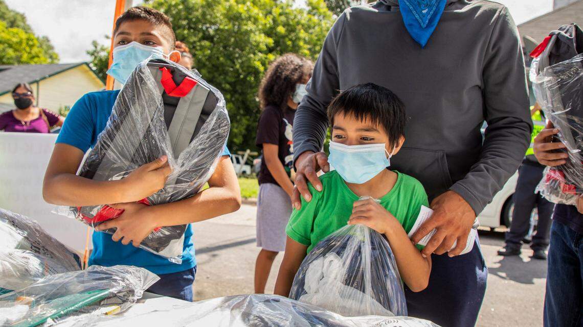From left, Brian Barajas, Pablo Alexis Barajas, their dad Pablo Barajas, and Christopher Barajas, pick up backpacks, school supplies, and lunch from the Durham Rescue Mission during its annual Back-To-School Pep Rally that was modified to be a drive-through event this year to reduce contact amid rising cases of COVID-19, on Wednesday, Aug. 18, 2021, in Durham, N.C.
