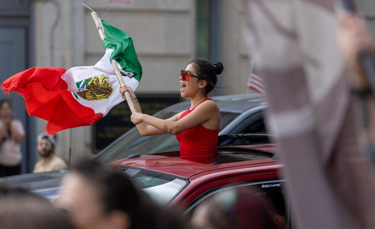 A demonstrator displays the flag of Mexico as they ride around the State Capitol square during the ‘No Kings’ rally on Saturday, June 14, 2025 in Raleigh, N.C.