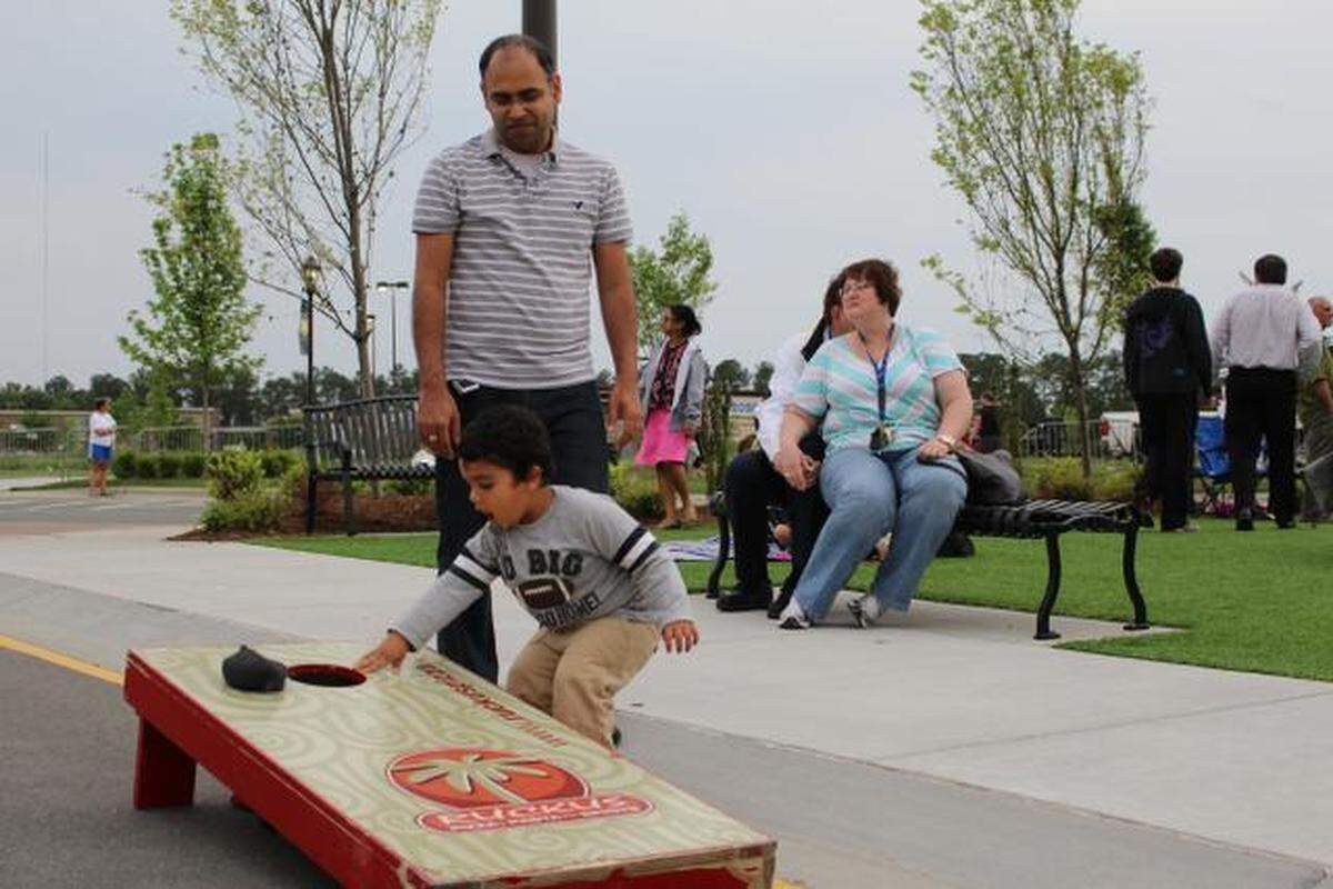 Two-year-old Satvik Arora plays cornhole with his father, Vikas Arora, during the LIVE in The District Music Series at Park West Village in Morrisville. 