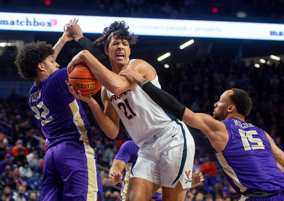 Virginia forward Kadin Shedrick (21) gets hung up between James Madison forward Julien Wooden (22) and guard Takal Molson (15) during the first half of an NCAA college basketball game in Harrisonburg, Va., Tuesday, Dec. 7, 2021.