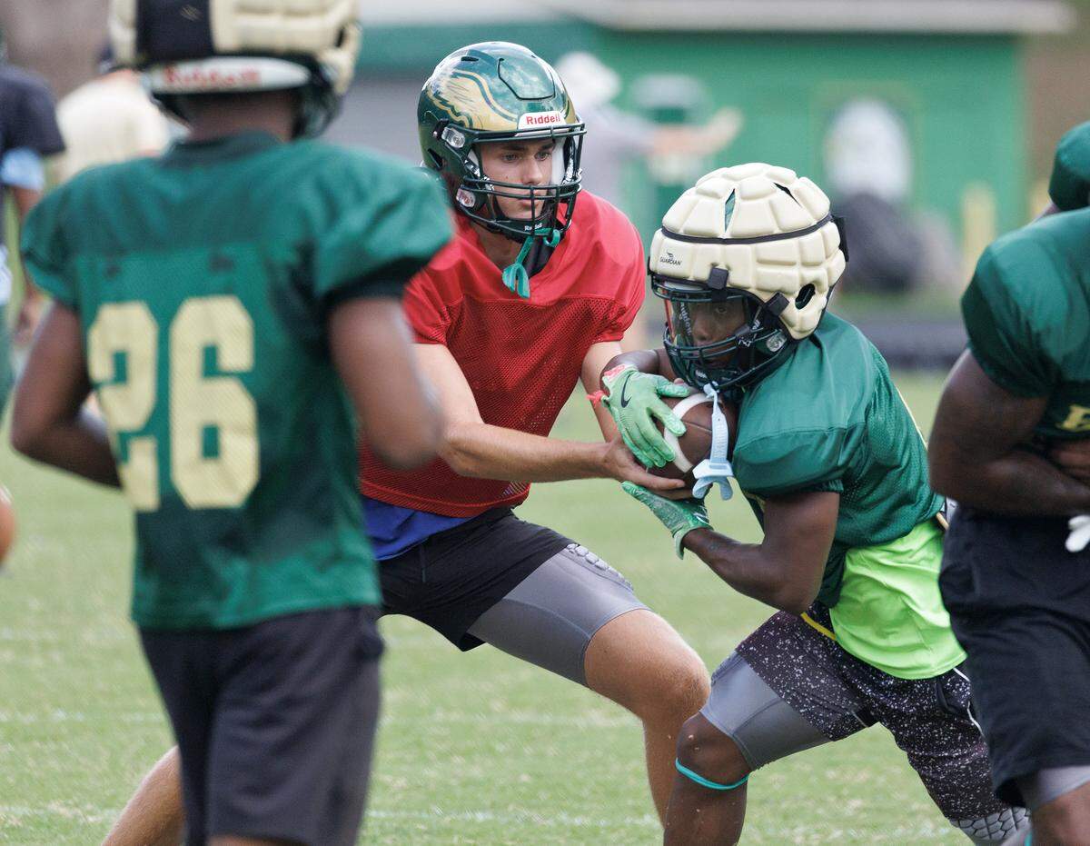 Enloe High School junior quarterback Leo Gorga hands the ball to senior running back Chase White during practice on Monday, Aug. 18, 2025, in Raleigh, N.C.