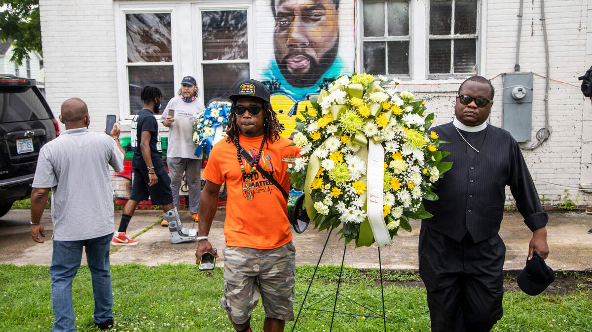 Demonstrators walk with a wreath near the site where Andrew Brown Jr. was shot and killed by Pasquotank County Sheriff deputies while serving a warrant in April. Around 150 protesters called for a special prosecutor and the release of body-camera footage in the Brown.