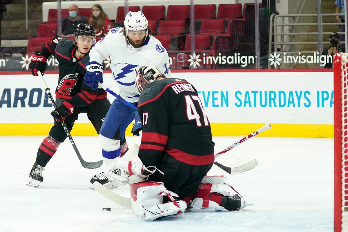 Tampa Bay Lightning left wing Pat Maroon (14) shoots against Carolina Hurricanes goaltender James Reimer (47) and Hurricanes defenseman Jake Bean (24) during the first period of an NHL hockey game in Raleigh, N.C., Saturday, March 27, 2021. (AP Photo/Gerry Broome)