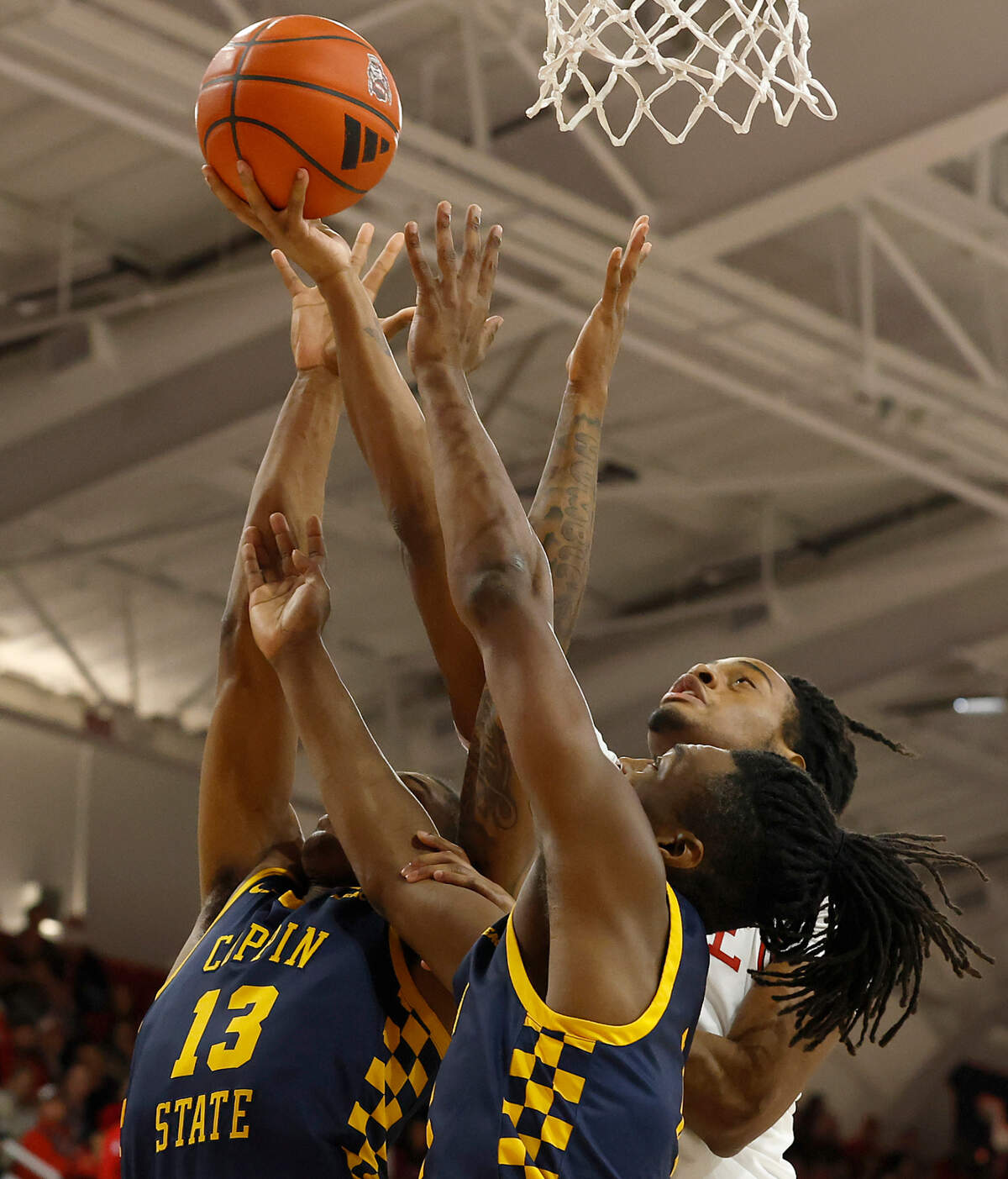 N.C. State’s Dennis Parker Jr. vies for a rebound with Coppin State’s Jonathan Dunn and Julius Ellerbe III during the first half of the Wolfpack’s 66-56 win on Tuesday, Dec. 10, 2024, at Reynolds Coliseum in Raleigh, N.C.