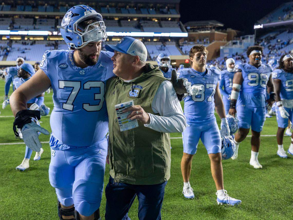 North Carolina offensive lineman Eli Sutton (73) embraces defensive coordinator Geoff Collins as they leave the field following the Tar Heels’ 31-24 victory over Wake Forest on Saturday, November 16, 2024 at Kenan Stadium in Chapel Hill, N.C.