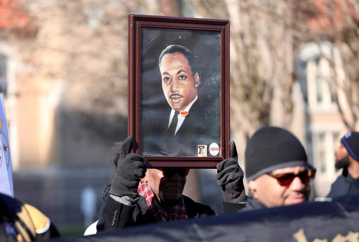 A man marching holds a painting of Martin Luther King Jr. during the Martin Luther King Jr. Day Unity March and Rally in Durham, N.C. on January 20, 2020.