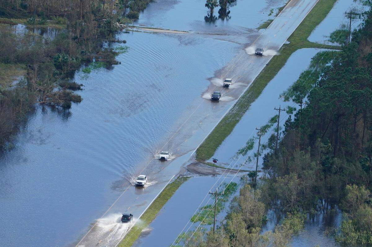 Cars drive on a flooded street caused by Hurricane Ian Thursday, Sept. 29, 2022, in Fort Myers, Fla. Climate change added at least 10% more rain to Hurricane Ian, a study prepared immediately after the storm shows.