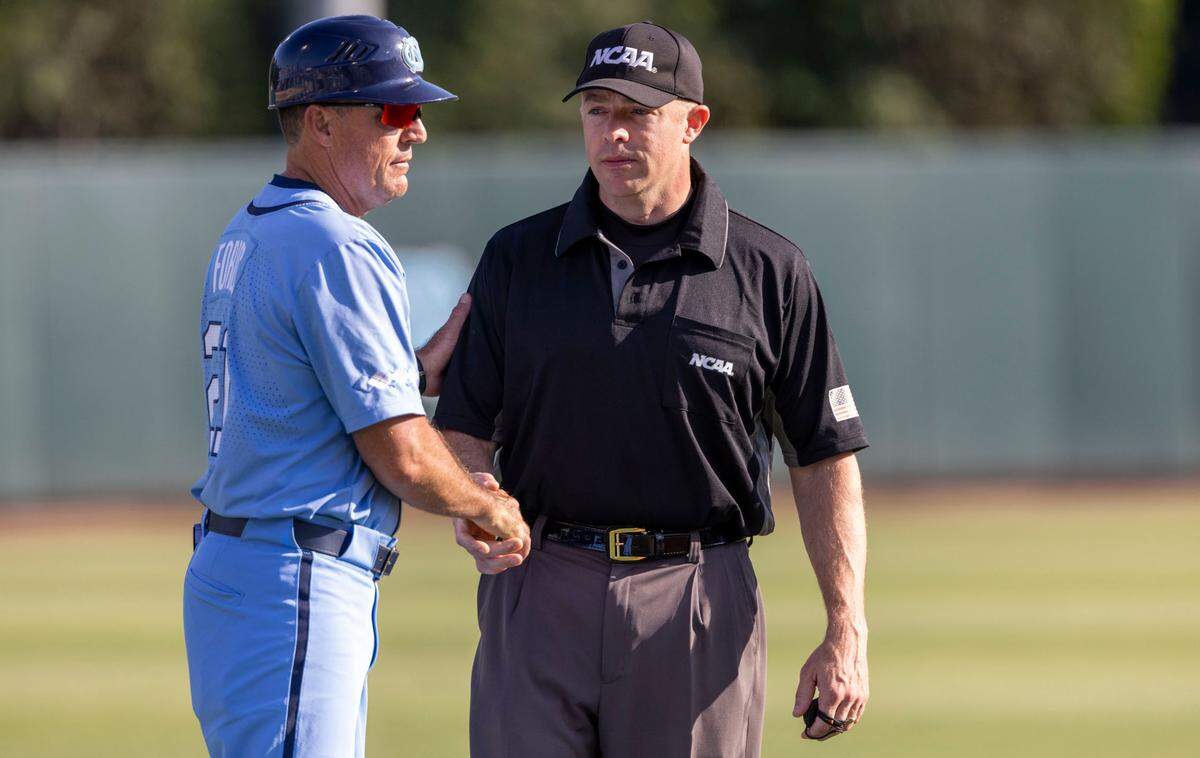 North Carolina coach Scott Forbes shakes hands with third base umpire Tim Rosso prior to the start of the Tar Heels’ game against VCU on Monday, June 6, 2022 at Boshamer Stadium in Chapel Hill, N.C. Forbes returned to coaching on Monday after being suspended for two games on Sunday.