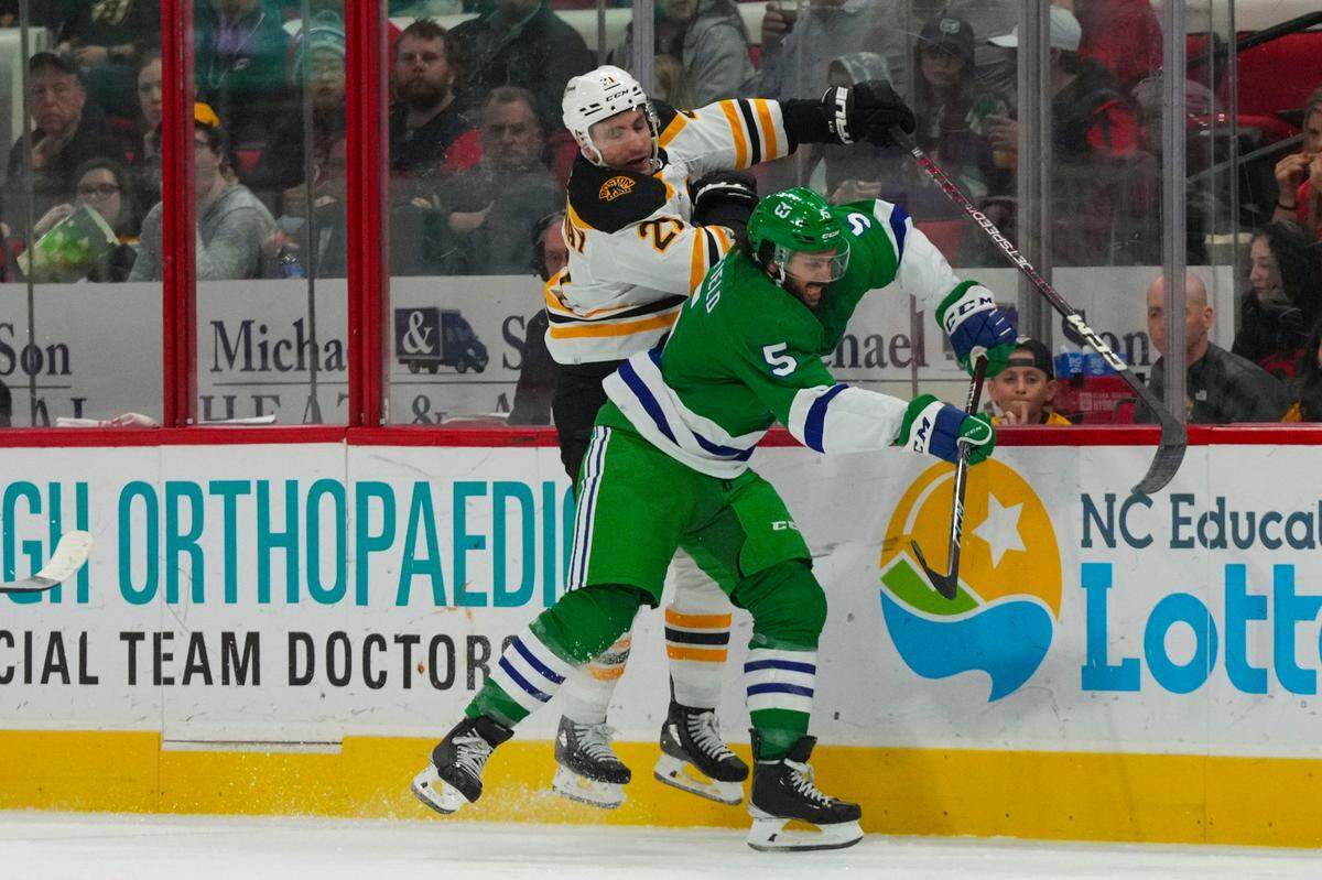 Carolina Hurricanes defenseman Jalen Chatfield (5) checks Boston Bruins right wing Garnet Hathaway (21) during the second period at PNC Arena.