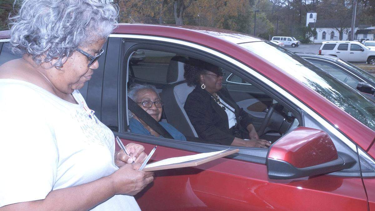 Margaret Myrick-Station assists 87-year-old Hattie Staton with curbside voting at the Edgecombe County Administration Building in Tarboro in November 2018.