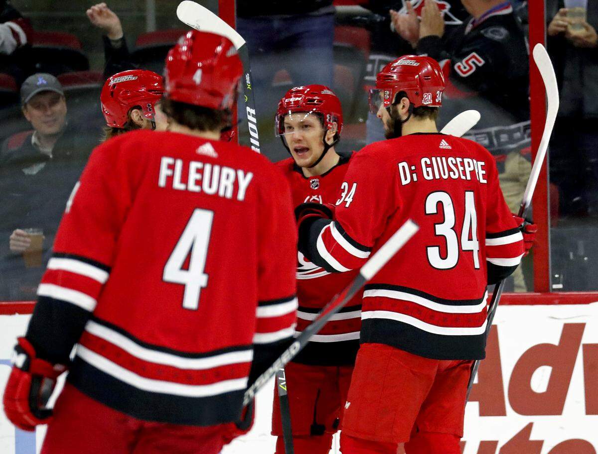 The Canes' Jeff Skinner (53) celebrates his goal with Haydn Fleury (4) and Phillip Di Giuseppe (34) during the first period.