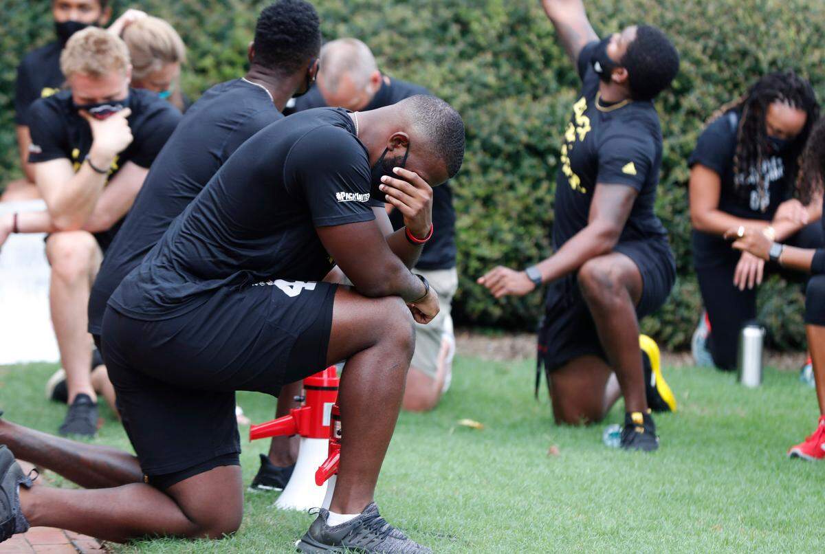 N.C. State’s Isaiah Moore, left, along with other Wolfpack athletes, coaches and staff kneel for 8:46, the time police kneeled on George Floyd, during a #PackUnited peaceful protest against racial and social injustice outside Holladay Hall on the campus of N.C. State Saturday, Sept. 12, 2020.