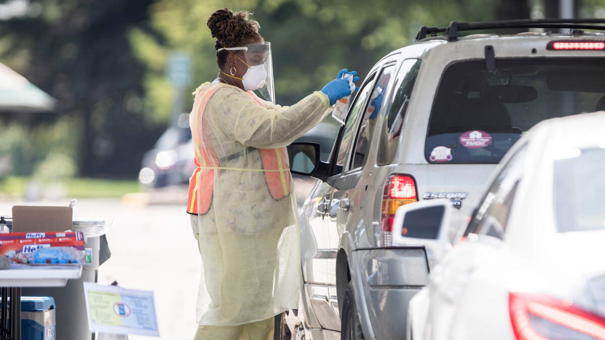 A nurse with Wake County Health and Human Services takes a completed COVID-19 test from a driver at a drive-thru testing site in the parking lot of the McKimmon Center in Raleigh, N.C. on Monday, July 6, 2020.