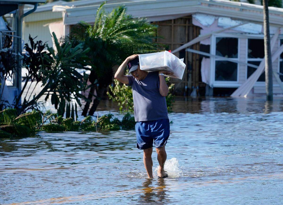 Tom Nugyn carries belongings from his flooded home after Hurricane Ian passed by the area Thursday, Sept. 29, 2022, in Fort Myers, Fla.