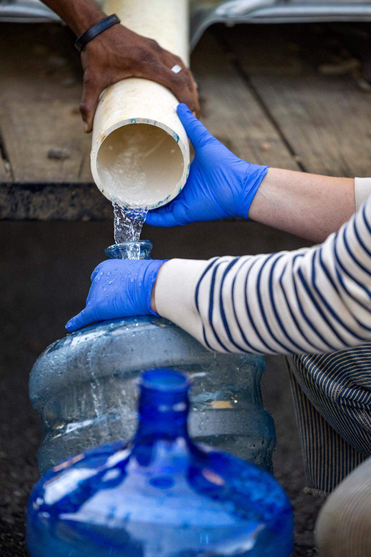 Volunteers with the grassroots group BeLoved Asheville, fill bottles of drinking water for residents in low-income independent living facilities, with no running water on Wednesday, October. 8, 2024. About half of Asheville’s water customers were still without running water this week because the remnants of Hurricane Helene ripped apart the city’s distribution system.
