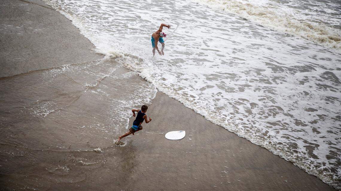 Skimboarders glide across the surf near the Ocean Crest Pier on Oak Island Monday, Aug. 3, 2020 as Tropical Storm Isaias moves towards the southeast coast. The storm is expected to strengthen to a hurricane before making landfall.